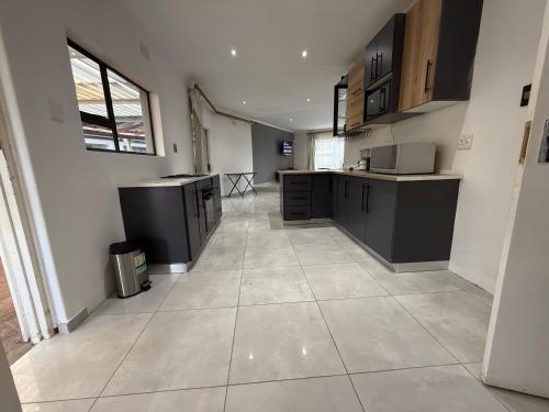 a large kitchen with black cabinets and a tile floor at Horizon Bed and Breakfast in Roodepoort