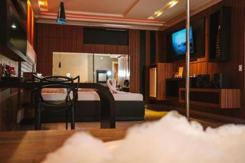 a bedroom with a bed and a table and a television at Romanus Piracicaba in Piracicaba