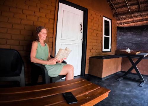 a woman sitting in a chair in front of a door at Safaria Lodge Wilpattu in Pahala Maragahawewa