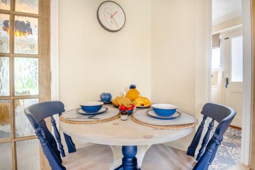 a dining room table with chairs and a clock on the wall at Firs End in North Walsham