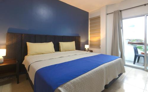 a bedroom with a large bed with a blue wall at Suite Arena, a pocos metros de la playa in Puerto Baquerizo Moreno