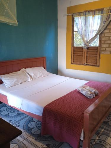 a bedroom with a large bed with a window at Hospedaria das Marias no Vale do Capão in Vale do Capao