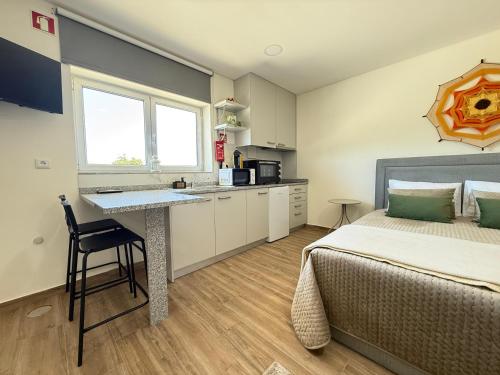 a bedroom with a bed and a desk and a kitchen at Suites de Braga in Braga
