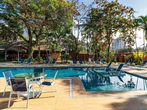 a pool with chairs and a table and a table and chairs at Novotel Sao Jose dos Campos in São José dos Campos