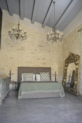 a bedroom with a bed and a mirror and chandeliers at Chiusa del prete 1867 in Noto