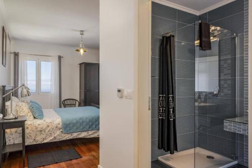 ein Bad mit einer Dusche und ein Schlafzimmer mit einem Bett in der Unterkunft Villa Casa Das Orquideas by Villa Plus in Estreito da Calheta