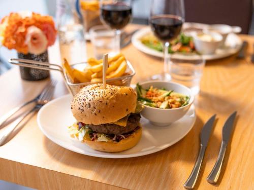 a plate of food with a hamburger and a bowl of fries at Novotel Brussels Airport in Diegem