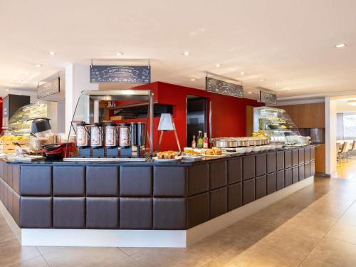 a restaurant with a counter with food on it at Novotel Brussels Airport in Diegem