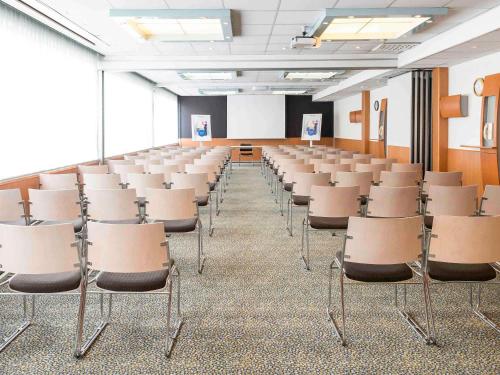 an empty room with rows of chairs in a classroom at Novotel Brussels Airport in Diegem