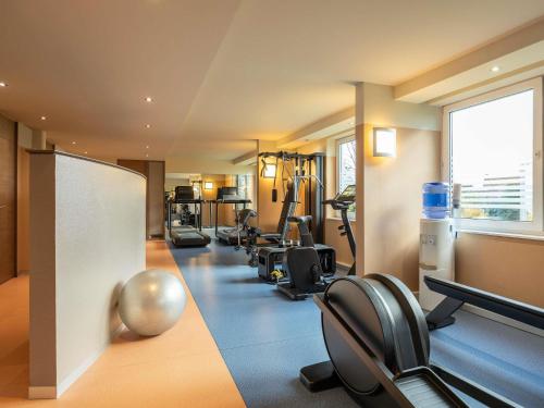 a gym with a row of treadmills and exercise bikes at Novotel Brussels Airport in Diegem
