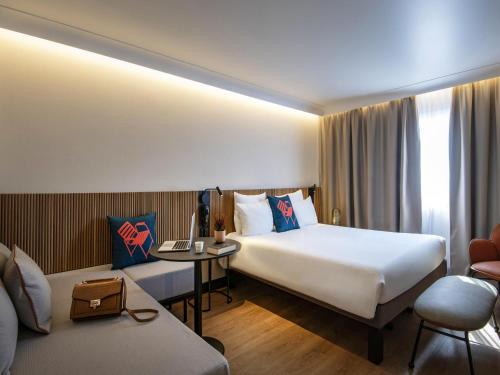 a hotel room with a bed and a desk with a laptop at Novotel Nice Arenas Aeroport in Nice