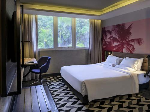 a hotel room with a bed and a desk and window at Novotel Sao Paulo Morumbi in Sao Paulo