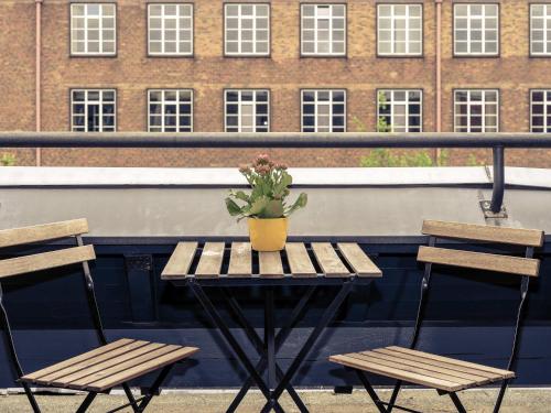a table with two chairs and a potted plant on a balcony at Mercure Hotel Berlin City West in Berlin