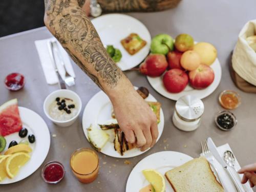 a person with their hand on a table with plates of food at Mercure Hotel Düsseldorf Neuss in Neuss