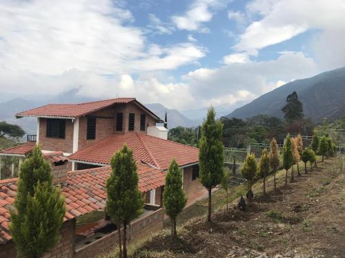 a house with a red roof and a row of trees at Casa Vacacional in Loja