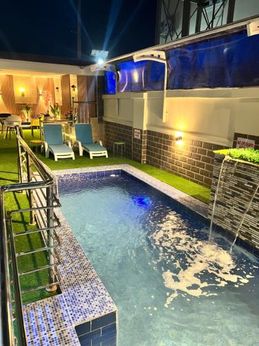a swimming pool at night with a table and chairs at Amia Gold Luxury Apartments in Abuja
