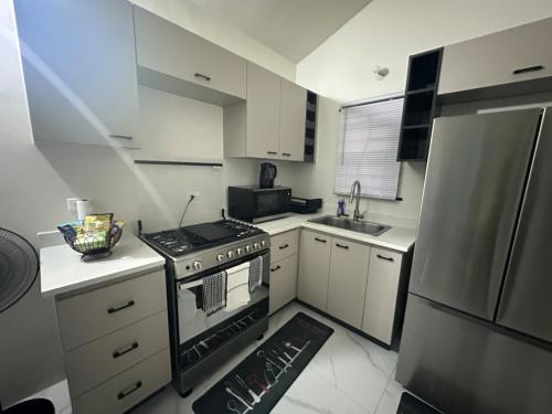 a small kitchen with a stove and a refrigerator at Zae's Retreat 2 bed 1 Bath in Portmore Jamaica in Newlands