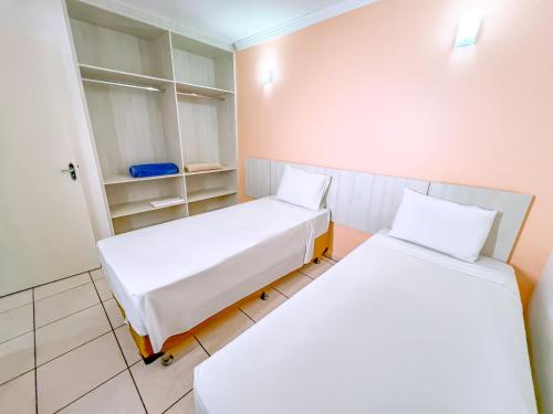 two beds in a room with white walls at diRoma Fiori direto com o Grupo diRoma com acesso ao Acqua Park e Café da manhã in Caldas Novas