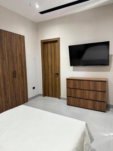 a bedroom with a bed and a flat screen tv at Trefa Suites in Reynosa