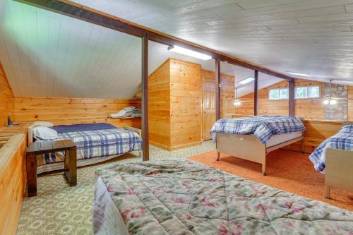 two beds in a room with wooden walls at Cabin Comfort Near PSU! Fire Pit and On-Site Trails in Gatesburg