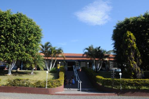 a building with trees and people sitting in a park at Hotel Fazenda Santa Maria in Serra Negra