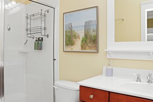 a bathroom with a toilet and a sink and a mirror at Barefoot Cottage B49 - Seabbatical by Pristine Properties Vacation Rentals in Highland View