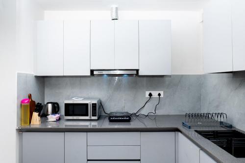 una cucina con armadi bianchi e un forno a microonde su un bancone di NivoNest a Gurgaon