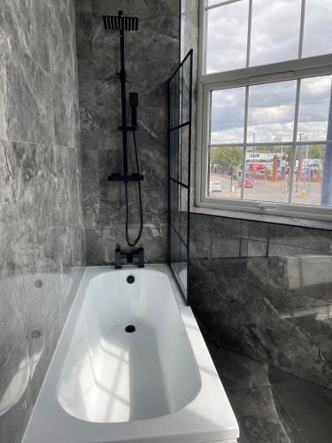 a white bath tub in a bathroom with a window at Stylish modern 2 bedroom flat 6B in Denton