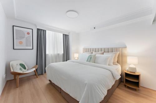a white bedroom with a large bed and a chair at Parkview in Johannesburg