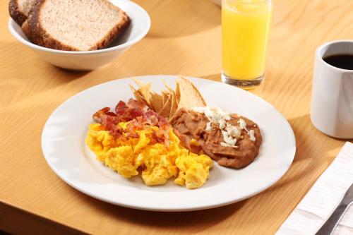 a plate of breakfast food with eggs bacon toast and orange juice at Holiday Inn Express Monterrey Galerias-San Jeronimo by IHG in Monterrey