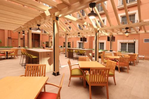 a cafeteria with wooden tables and chairs and tables at Holiday Inn Express Monterrey Galerias-San Jeronimo by IHG in Monterrey