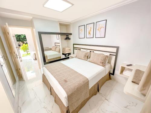 Un dormitorio blanco con una cama grande y un espejo. en diRoma Resort direto com o Grupo diRoma com acesso ao Acqua Park e Café da manhã, en Caldas Novas