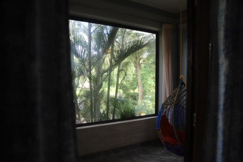 a window with a view of a palm tree at Sera Crest by Hola Goa in Jāmb
