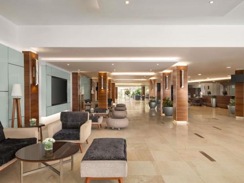 a lobby with chairs and tables in a building at Novotel Cairo Airport in Cairo