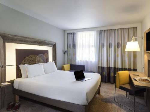 a hotel room with a bed with a laptop on it at Novotel Coventry in Coventry