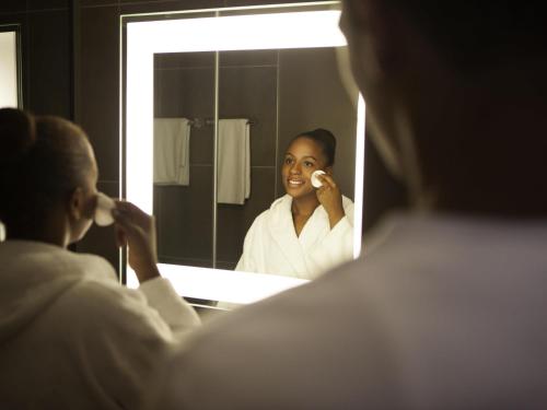 a woman talking on a phone in front of a mirror at Novotel Coventry in Coventry