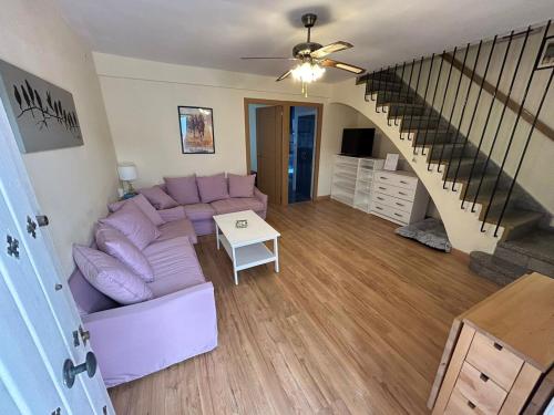 Una sala de estar con un sofá morado y una escalera. en Casa unifamiliar con patio céntrica y tranquila, en Sanlúcar de Barrameda