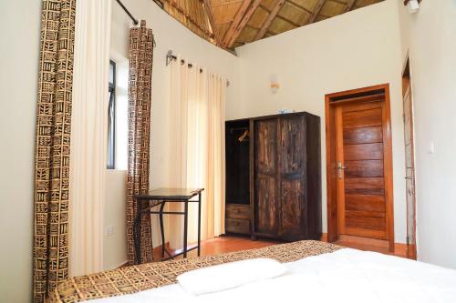 una camera da letto con un letto e una porta di legno di Lake Muhazi Villa, Up to 12 Guests a Rwamagana