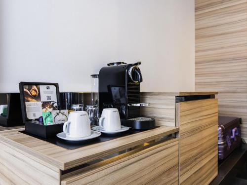 a counter with cups and a coffee maker on it at Novotel Amsterdam City in Amsterdam