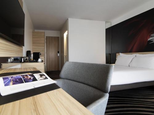 a bedroom with a bed and a chair and a table at Novotel Amsterdam City in Amsterdam