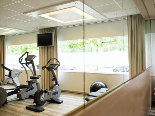 a gym with exercise equipment and a large window at Novotel Rotterdam - Schiedam in Schiedam