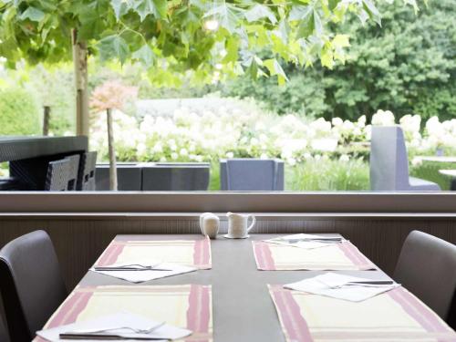 a table in a restaurant with a view of a garden at Novotel Rotterdam - Schiedam in Schiedam