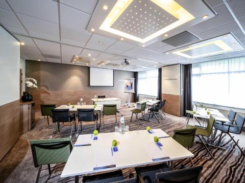 a conference room with tables and chairs and a projection screen at Novotel Rotterdam - Schiedam in Schiedam