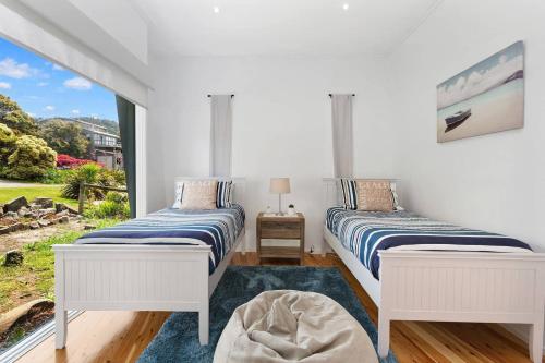 Dos camas en una habitación con ventana. en COASTAL HAVEN - panoramic ocean views, en Skenes Creek