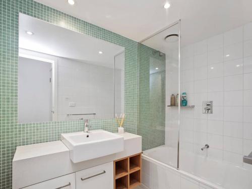 un bagno con un lavandino, una vasca e uno specchio di APOLLO BLUE 4 - modern waterfront apartment a Apollo Bay