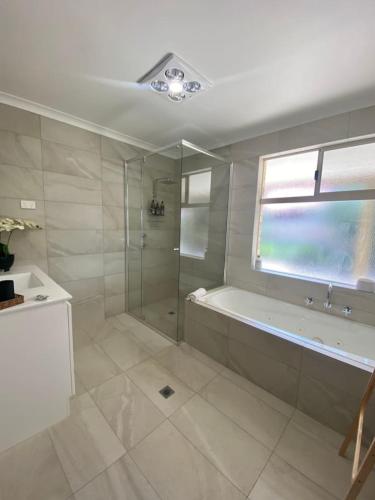 a bathroom with a shower and a tub and a window at A Wave from It All Esperance in Esperance