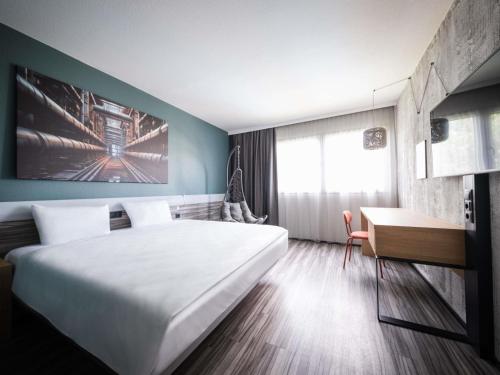 a hotel room with a large bed and a desk at Ibis Styles Linz in Linz