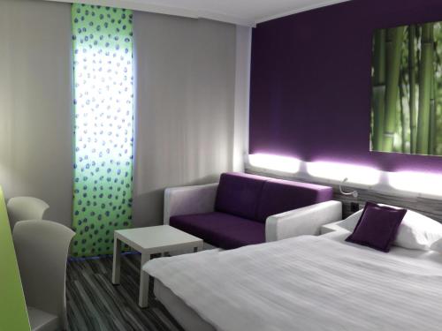 a room with a bed and a couch and a chair at Ibis Styles Linz in Linz
