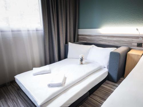 a bed with a teddy bear sitting on top of it at Ibis Styles Linz in Linz