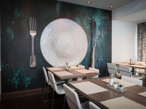 a dining room with tables and a large plate on the wall at Ibis Styles Linz in Linz